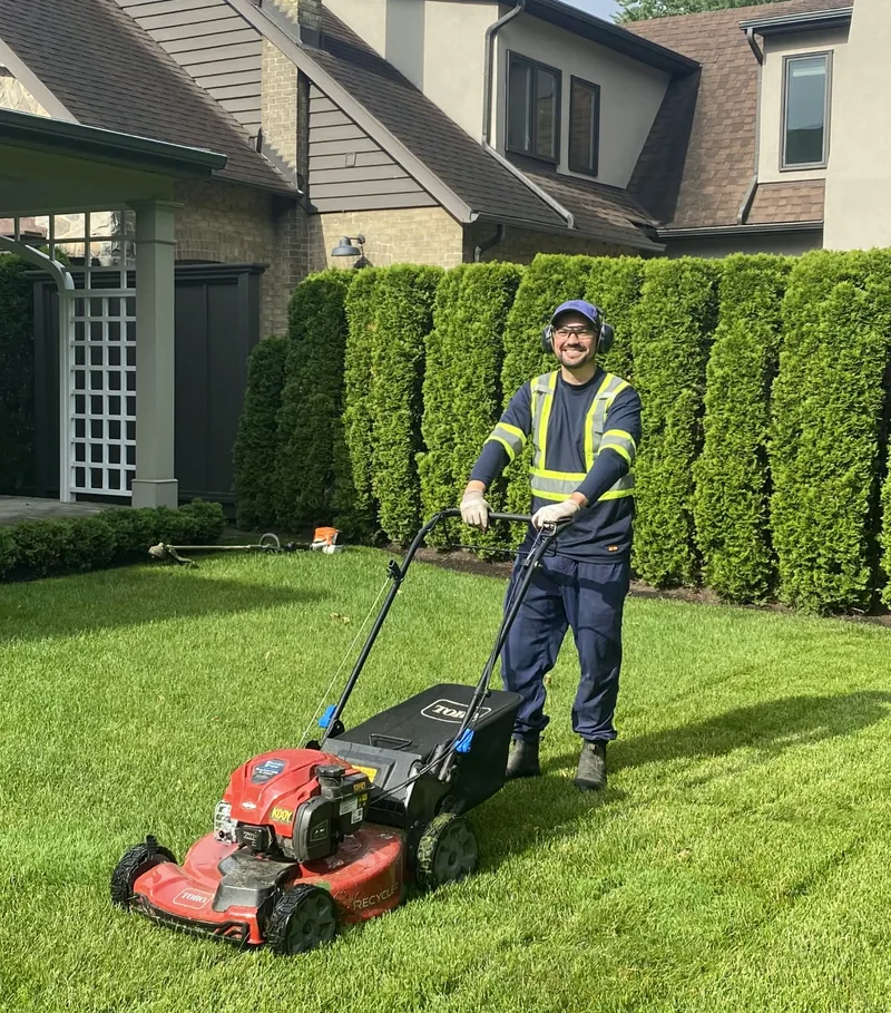A Clover team member operating a lawn mower at a residential property